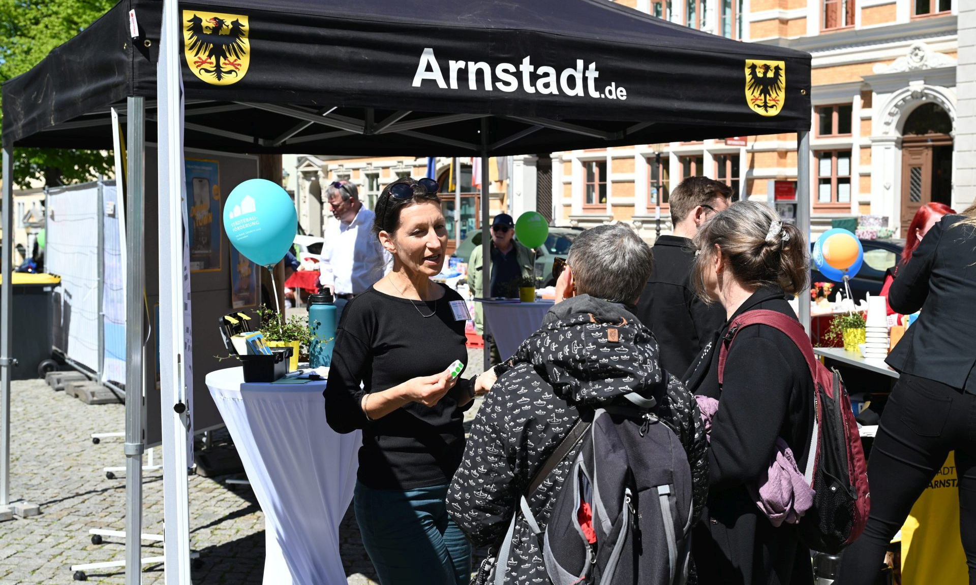 Ein Pavillon mit der Aufschrift Arnstadt.de, eine Frau, die mit anderen Menschen spricht