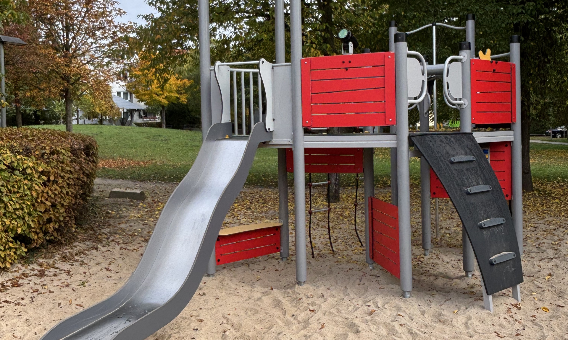 Rotes Spielplatzelement mit Rutsche und Leiter sowie Klettermöglichkeiten