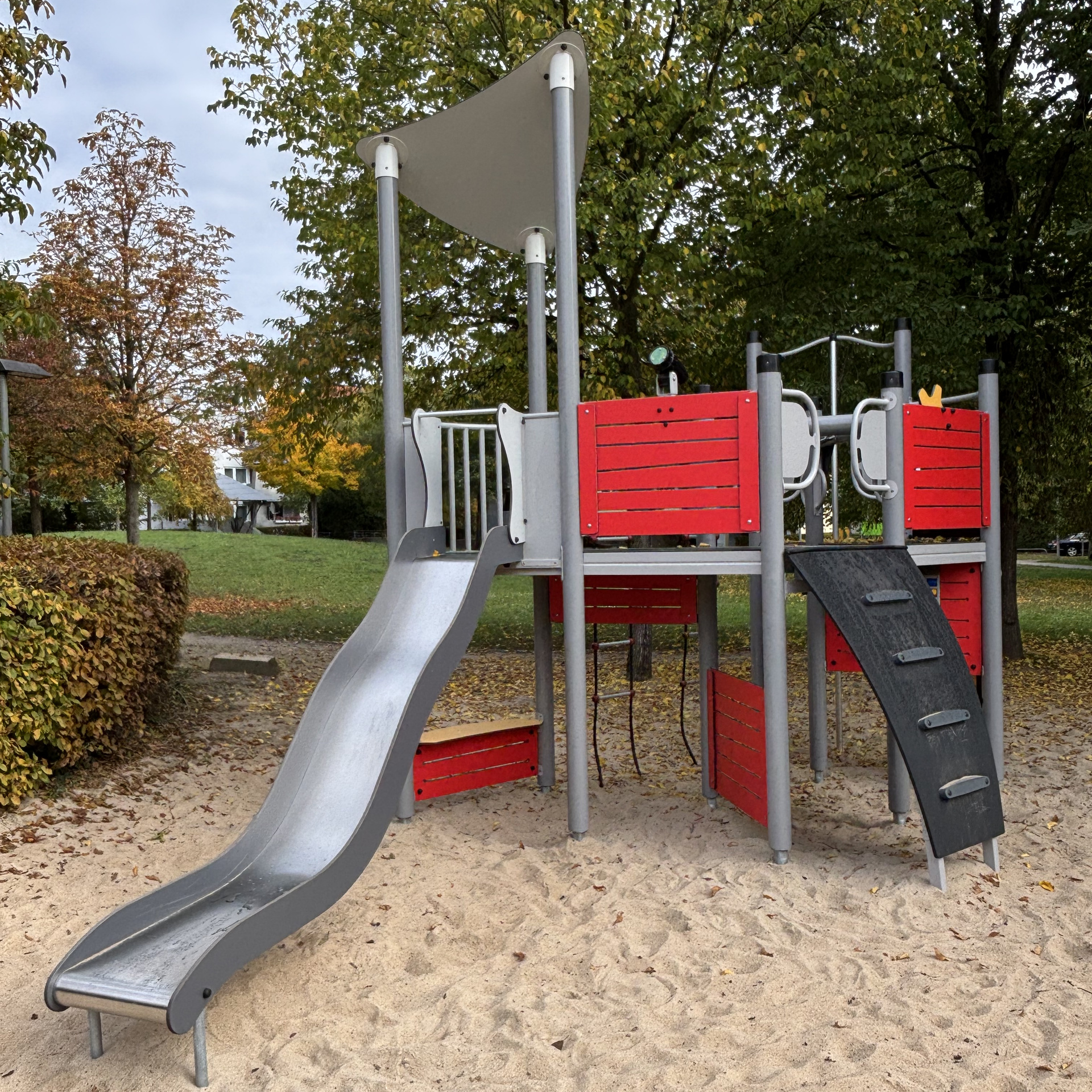 Rotes Spielplatzelement mit Rutsche und Leiter sowie Klettermöglichkeiten
