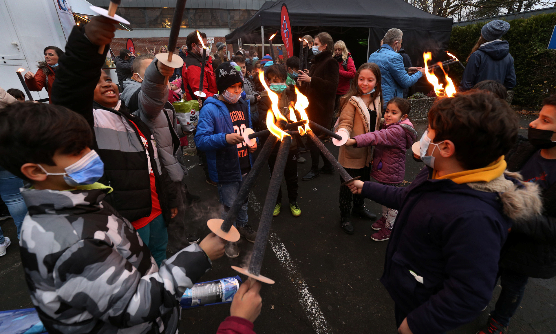 Kinder halten ihre brennenden Fackeln zusammen.