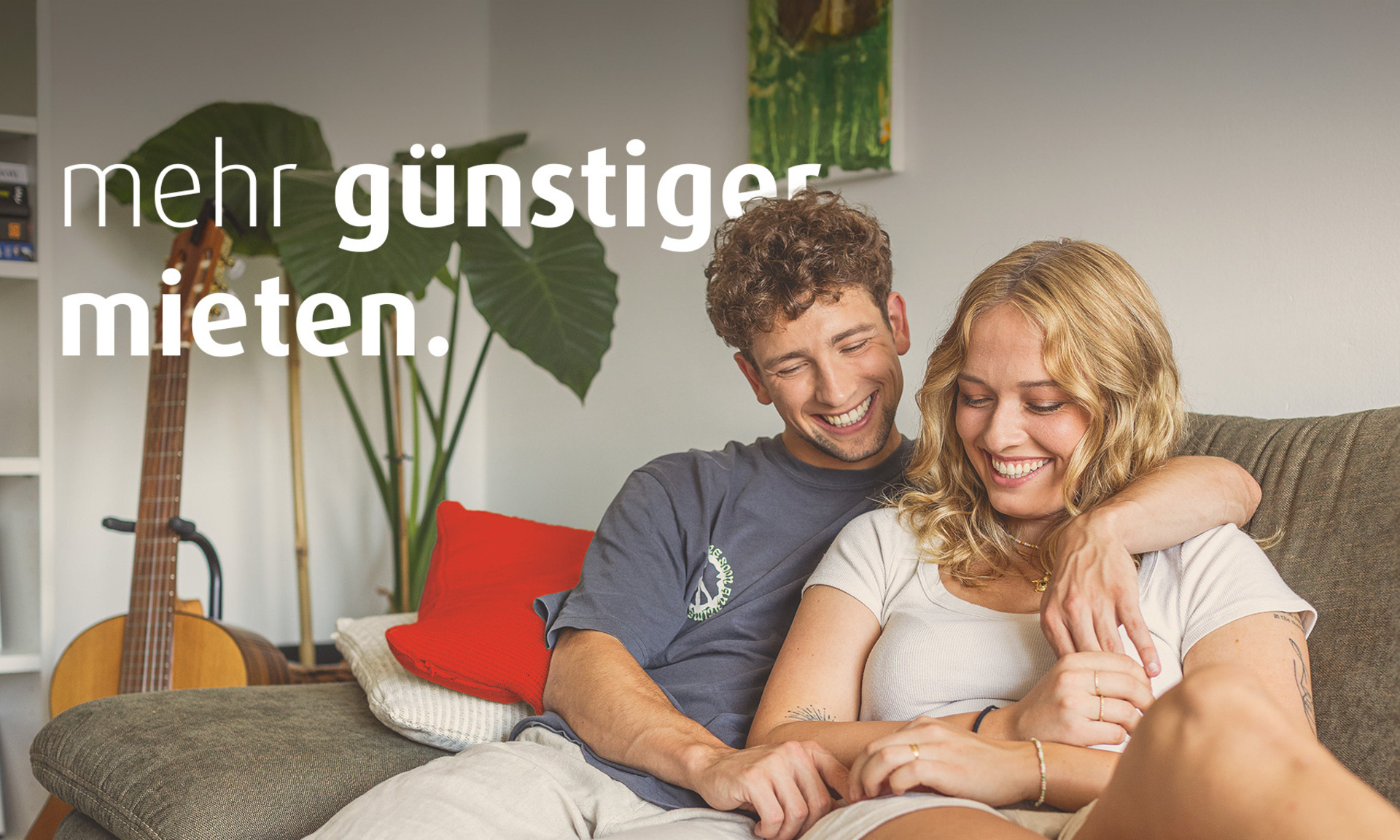 Ein junger Mann und eine junge Frau sitzen gemeinsam auf dem Sofa. Der Mann hat den Arm um die Frau gelegt. Auf dem Bild steht der Text "mehr günstiger mieten".