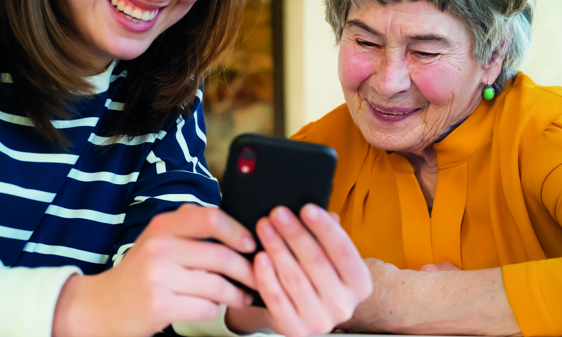 Senioren und junge Frau beugen sich über ein Handy
