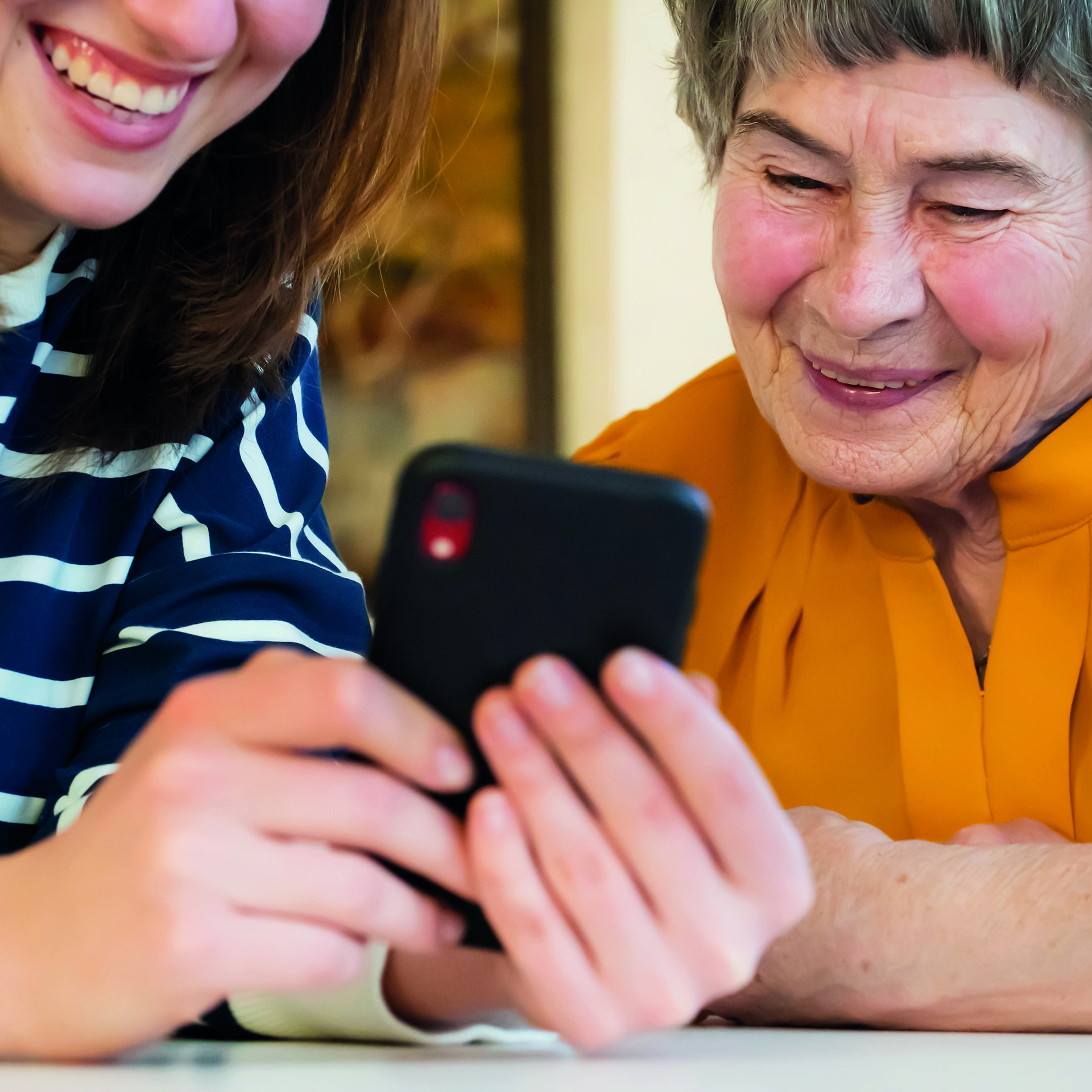 Senioren und junge Frau beugen sich über ein Handy