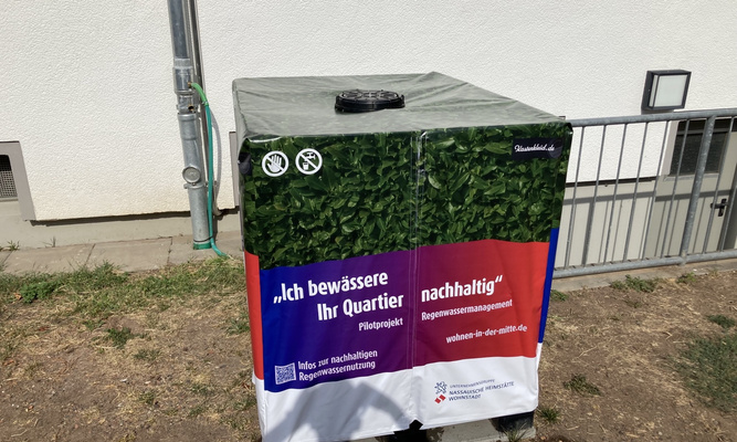 Eingehüllte Regentonne vor Hauswand