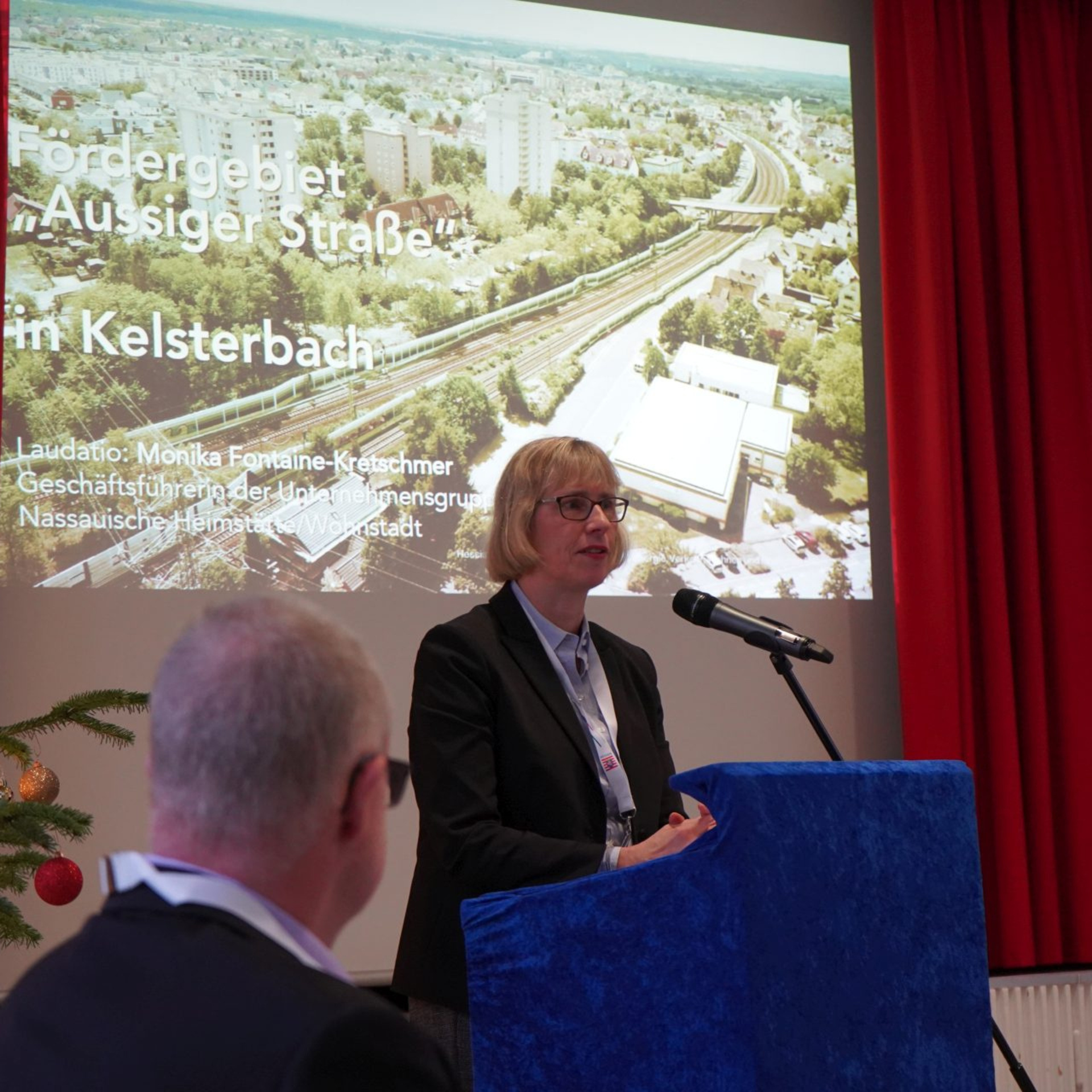 NHW-Geschäftsführerin Monika Fontaine-Kretschmer bei ihrer Laudatio für das Fördergebiet in Kelsterbach. Foto: Ministerium am Mikrofon