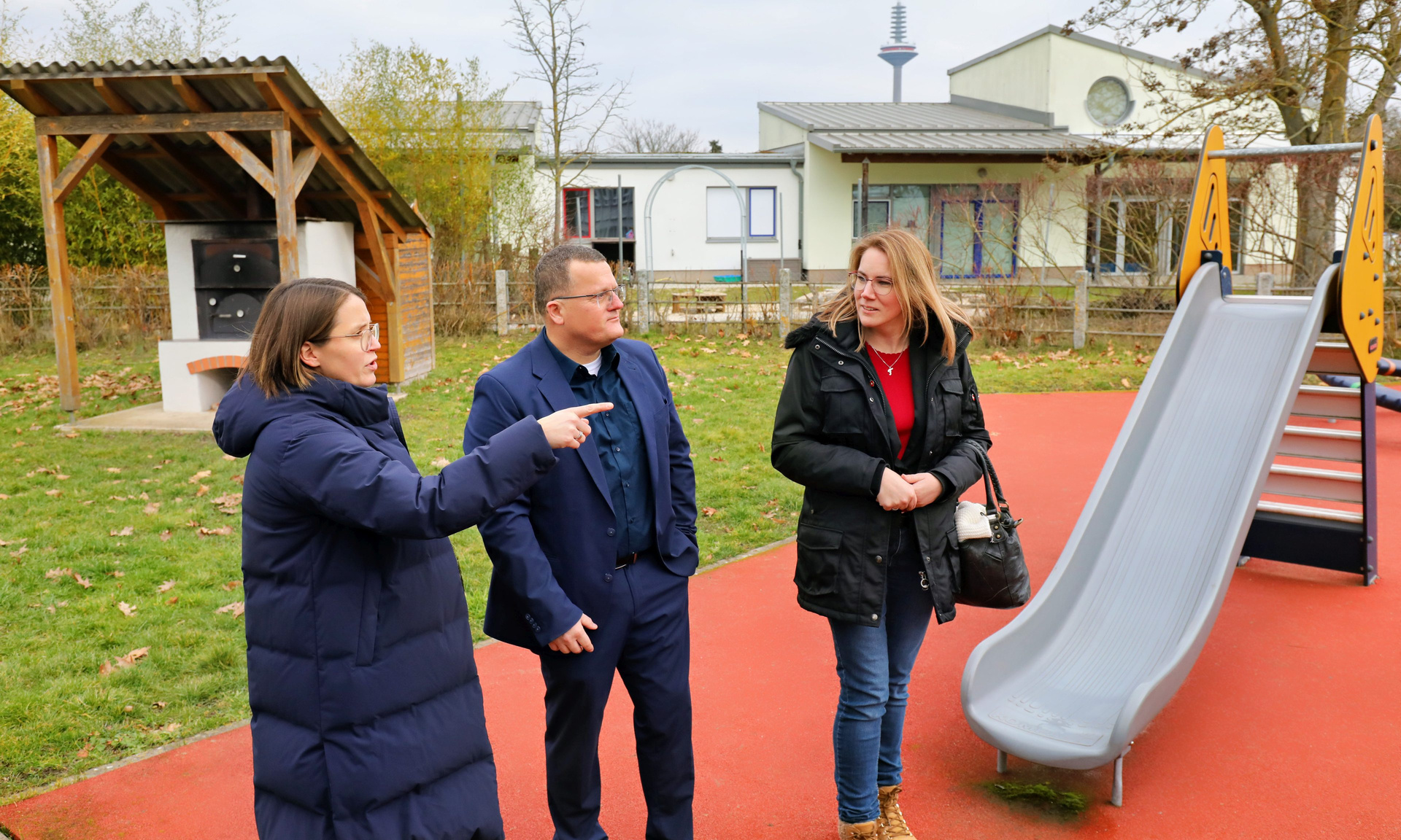 Lebenshilfe-Vorständin Dominique Deneu (li.) gab Regionalcenterleiter Holger Lack und Servicecenterleiterin Sina Jansohn bei einem Rundgang einen umfassenden Einblick in die Arbeit der Lebenshilfe Frankfurt.  Im Hintergrund eine Rutsche und ein Kita-Gebäude