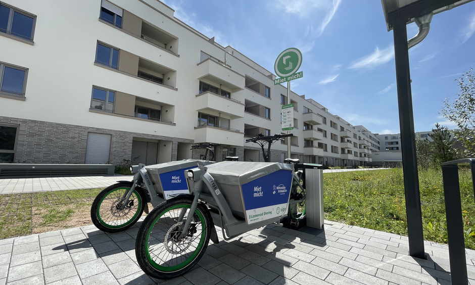 Zwei E-Lastenräder stehen vor einem Gebäude.