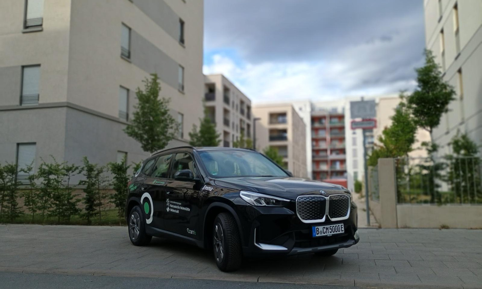 schwarzer moderner BMW steht vor einem Neubaugebiet