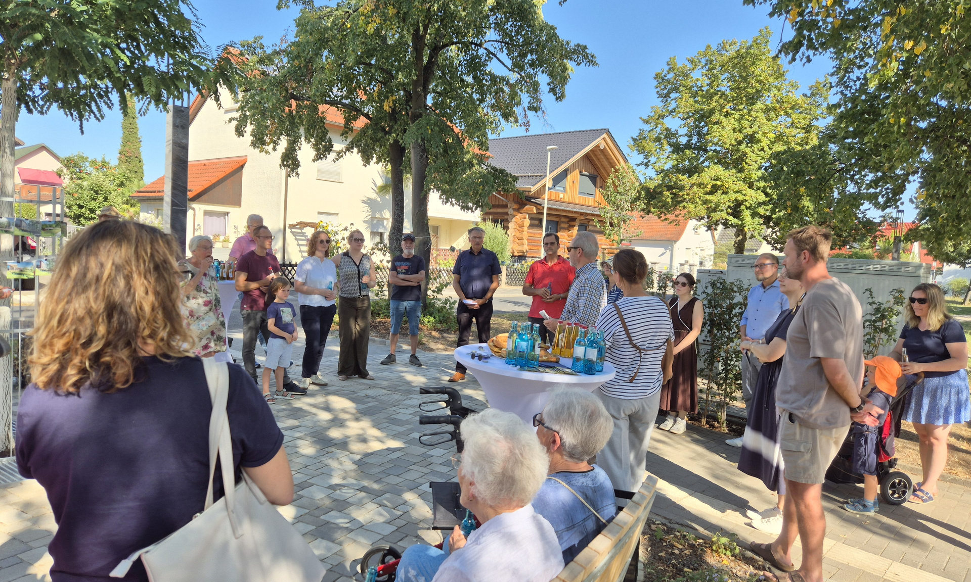 Feier mit rund 20 Menschen und einem neugestalteten Platz in Kelsterbach mit Bäumen, Bänken und Getränken