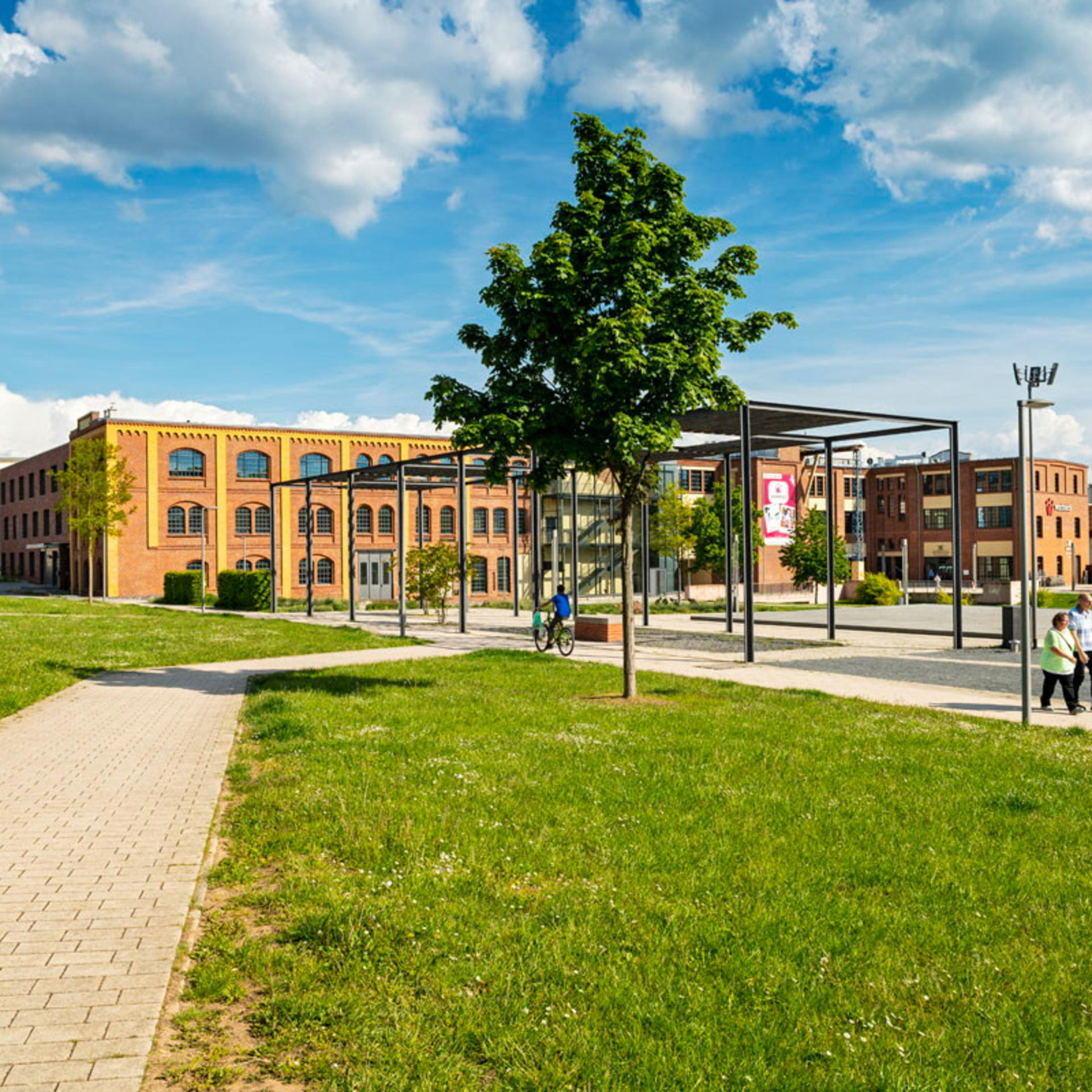 Grüne Wiese mit Fußweg, im Hintergrund altes Fabrikgebäude im Schilde-Park in Bad Hersfeld