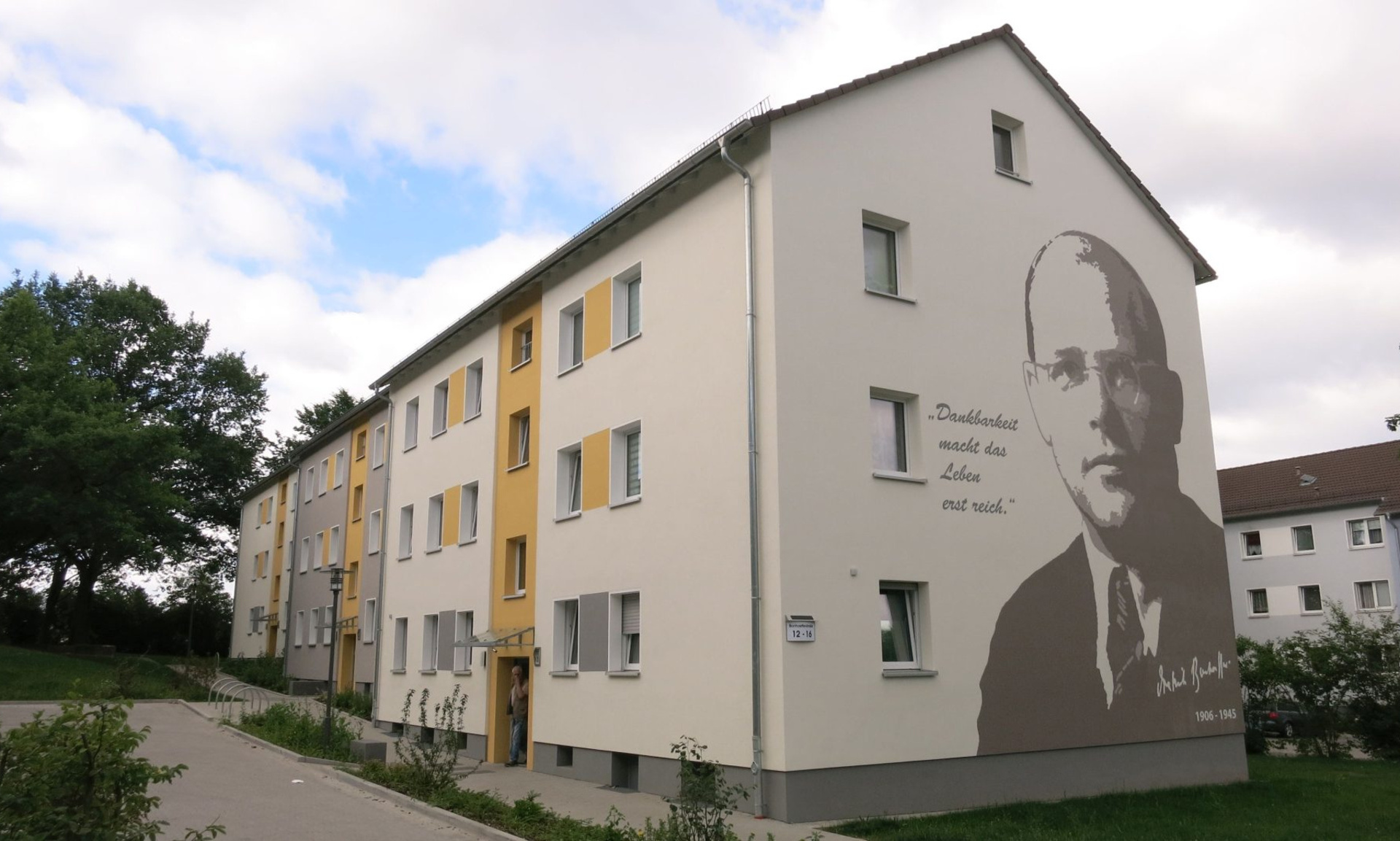 Blick auf die Fassade eines modernisierten Mehrfamilienhauses mit einem Mural an der Seitenwand