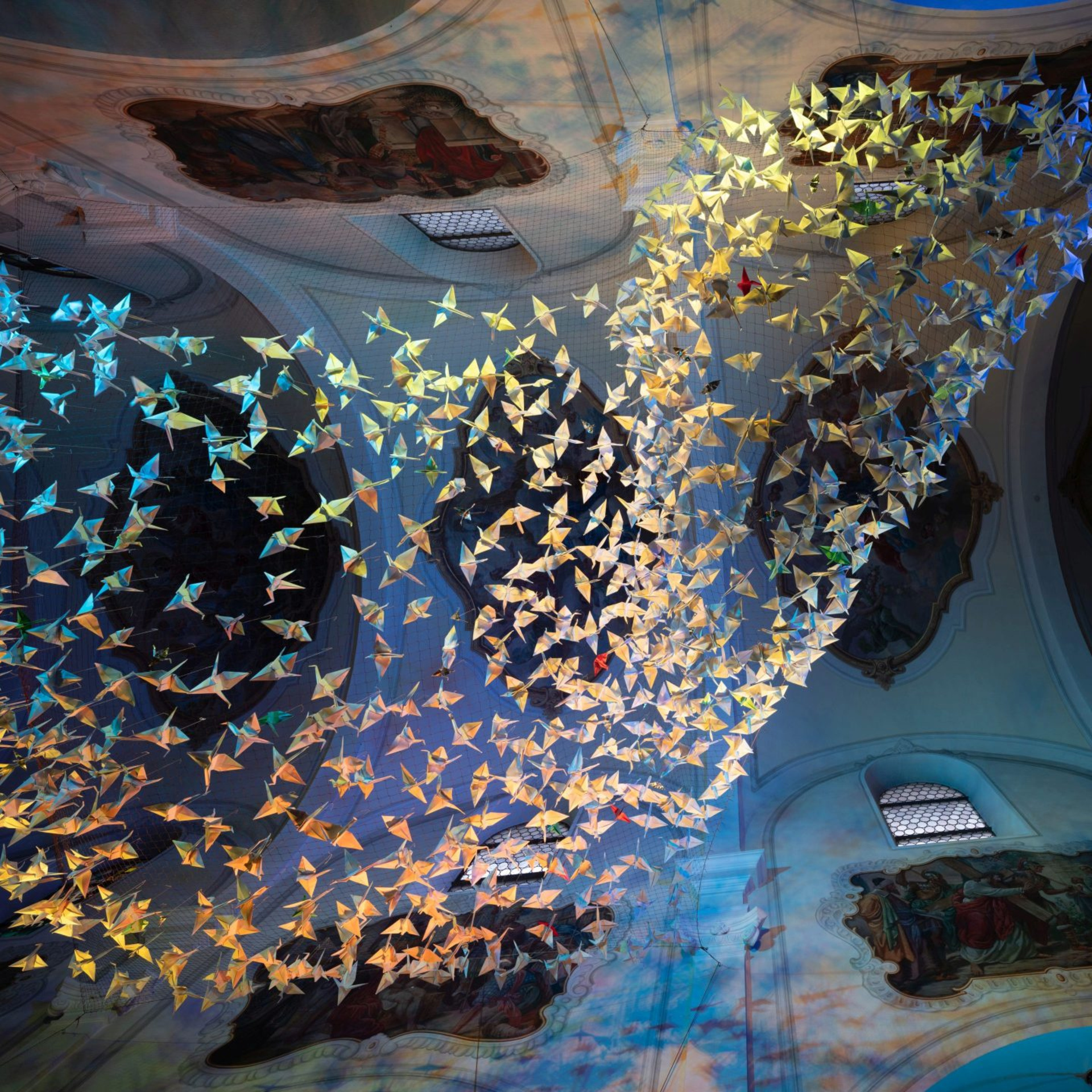 Blick nach oben in der Kelsterbacher Herz-Jesu-Kirche auf 843 Origami-Kraniche - hier golden illuminiert.