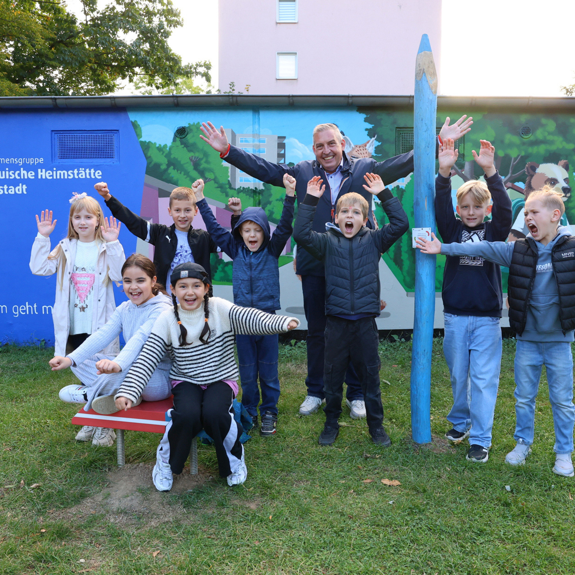 Gruppe von Jugendlichen vor einer gestalteten Garagenwand. Auf der Wand ist das NHW Logo zu sehen