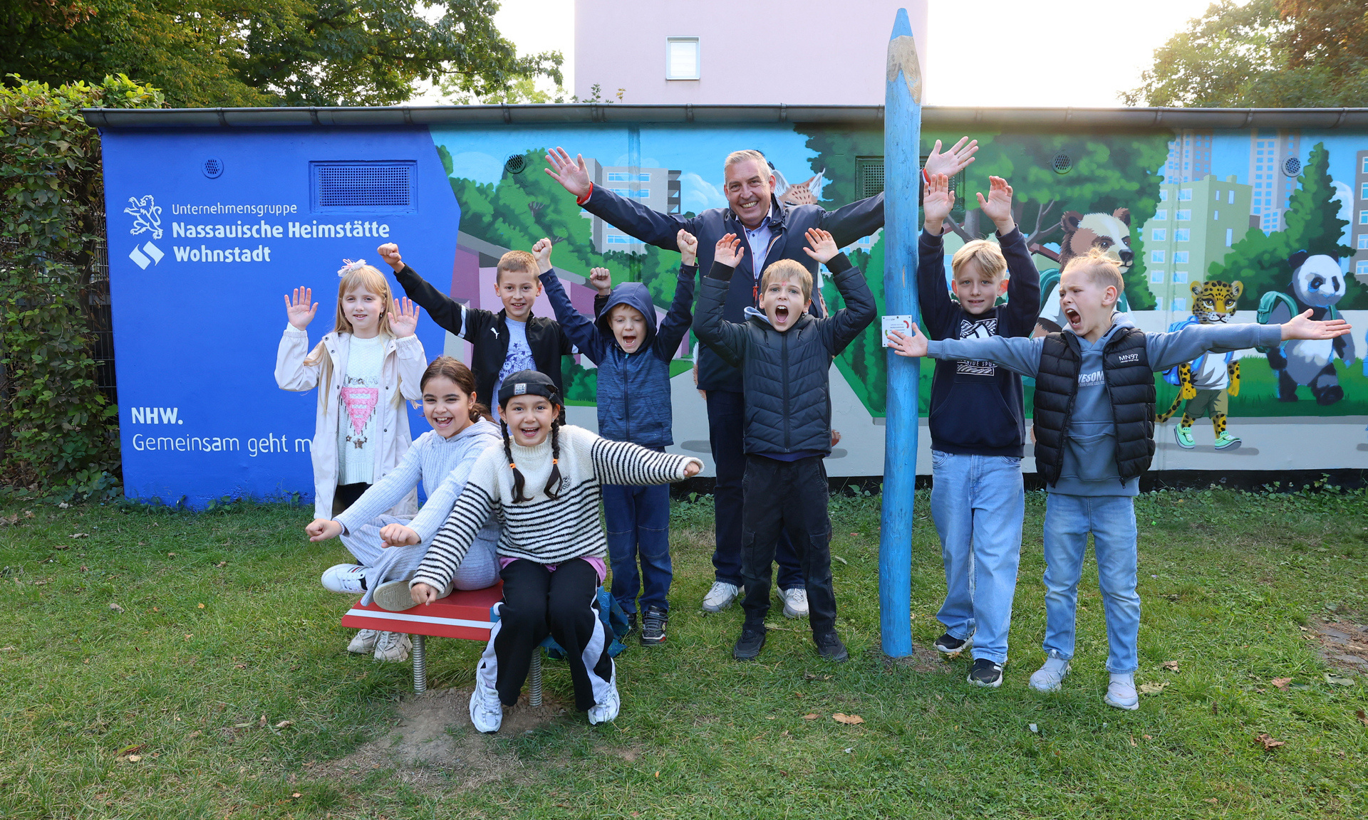 Gruppe von Jugendlichen vor einer gestalteten Garagenwand. Auf der Wand ist das NHW Logo zu sehen