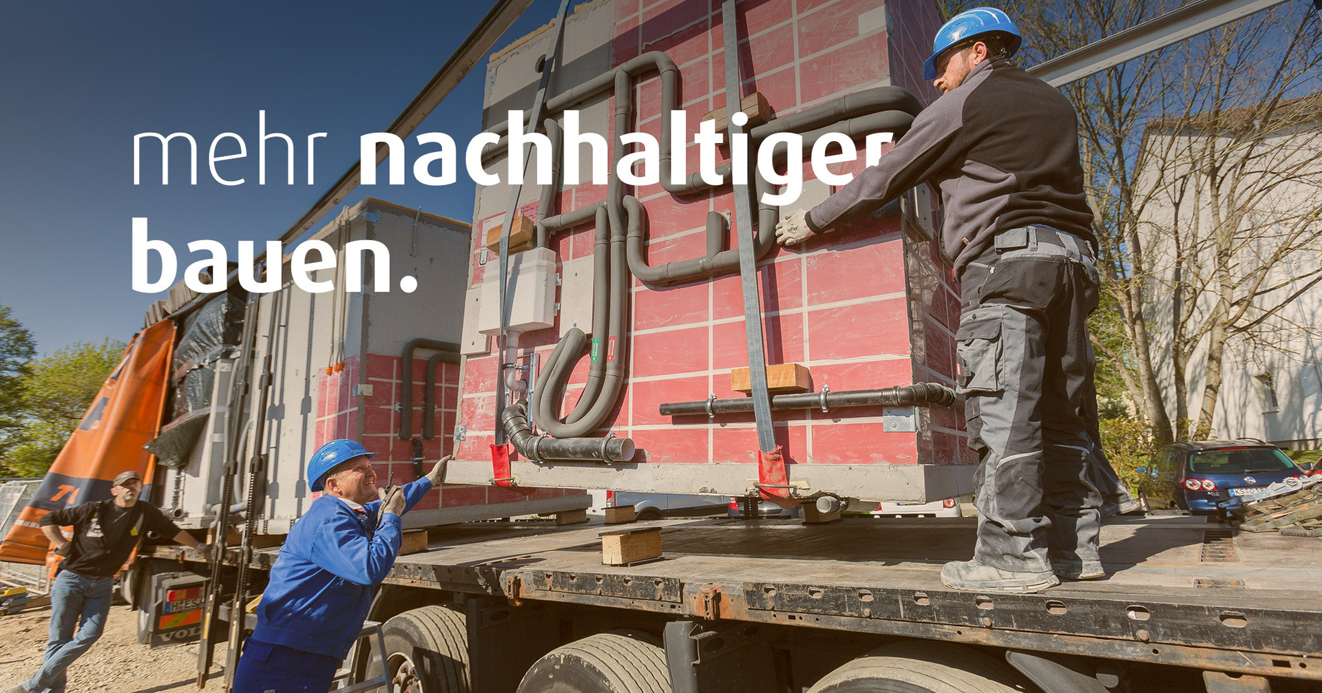 Zwei Männer in Baustellenkleidung entladen einen Lastwagen, der ein Modul für die Baustelle angeliefert hat. Auf dem Bild steht der Text "mehr nachhaltiger bauen".