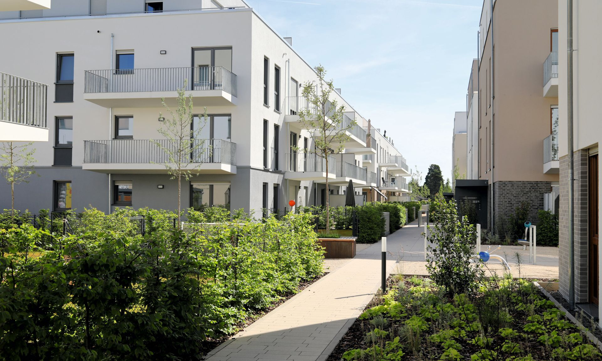 Neugebaute mehrgeschossige Häuser. Ein Weg führt zwischen den Häusern durch.