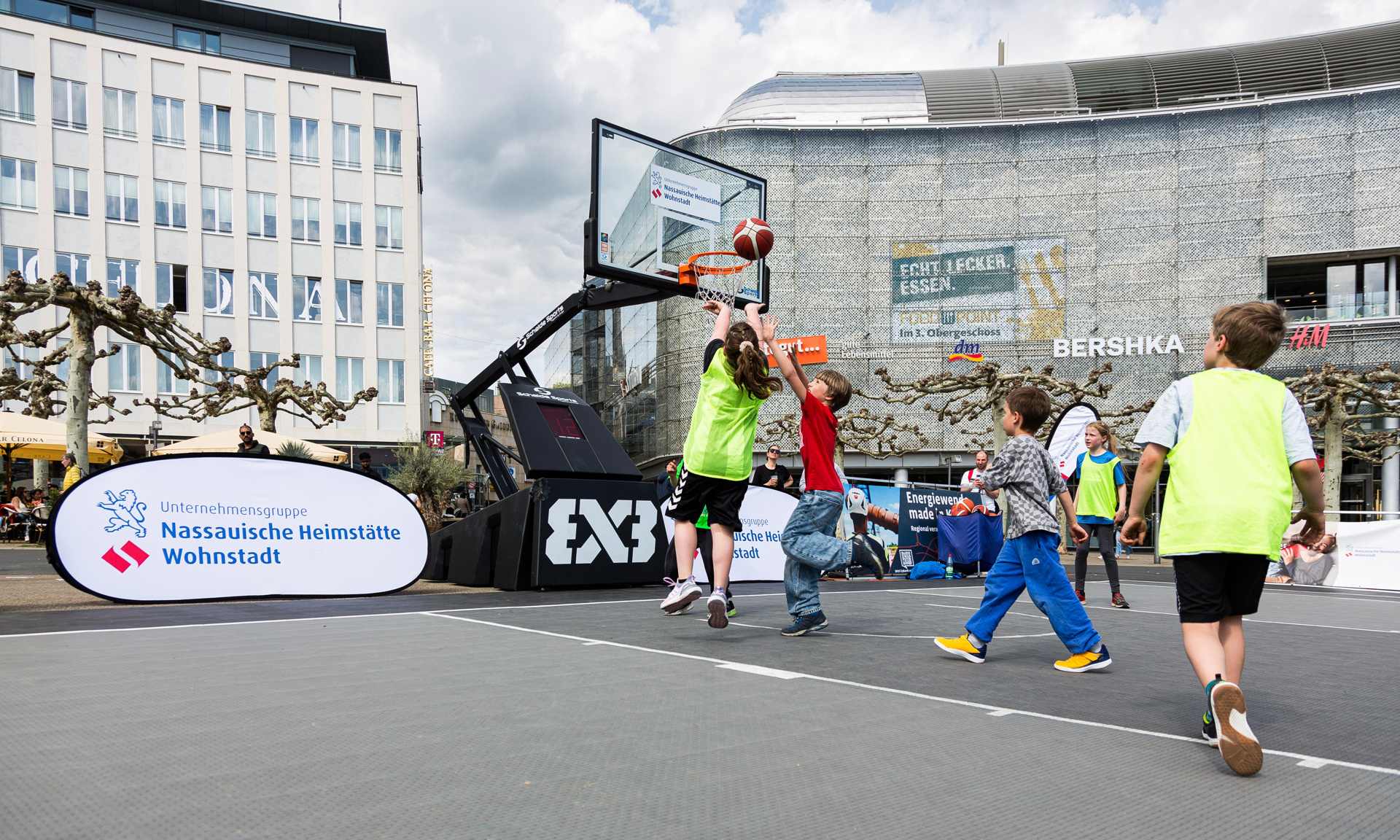 Mehrere Kinder spielen auf einem Street Court Basketball