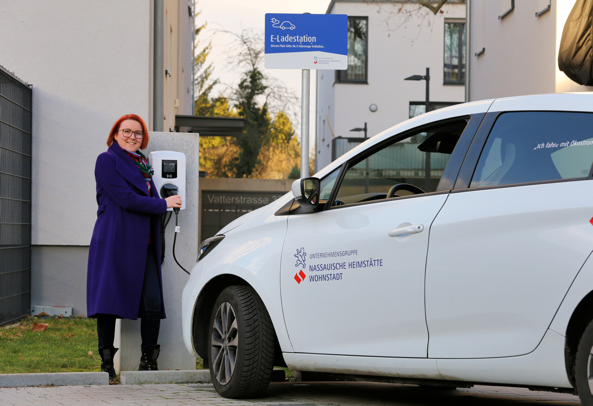 Frau an E-Tankstelle mit Auto.