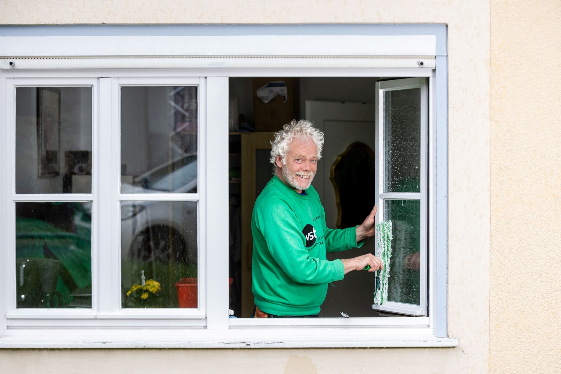 Ein WST-Mitarbeiter putzt ein Fenster.