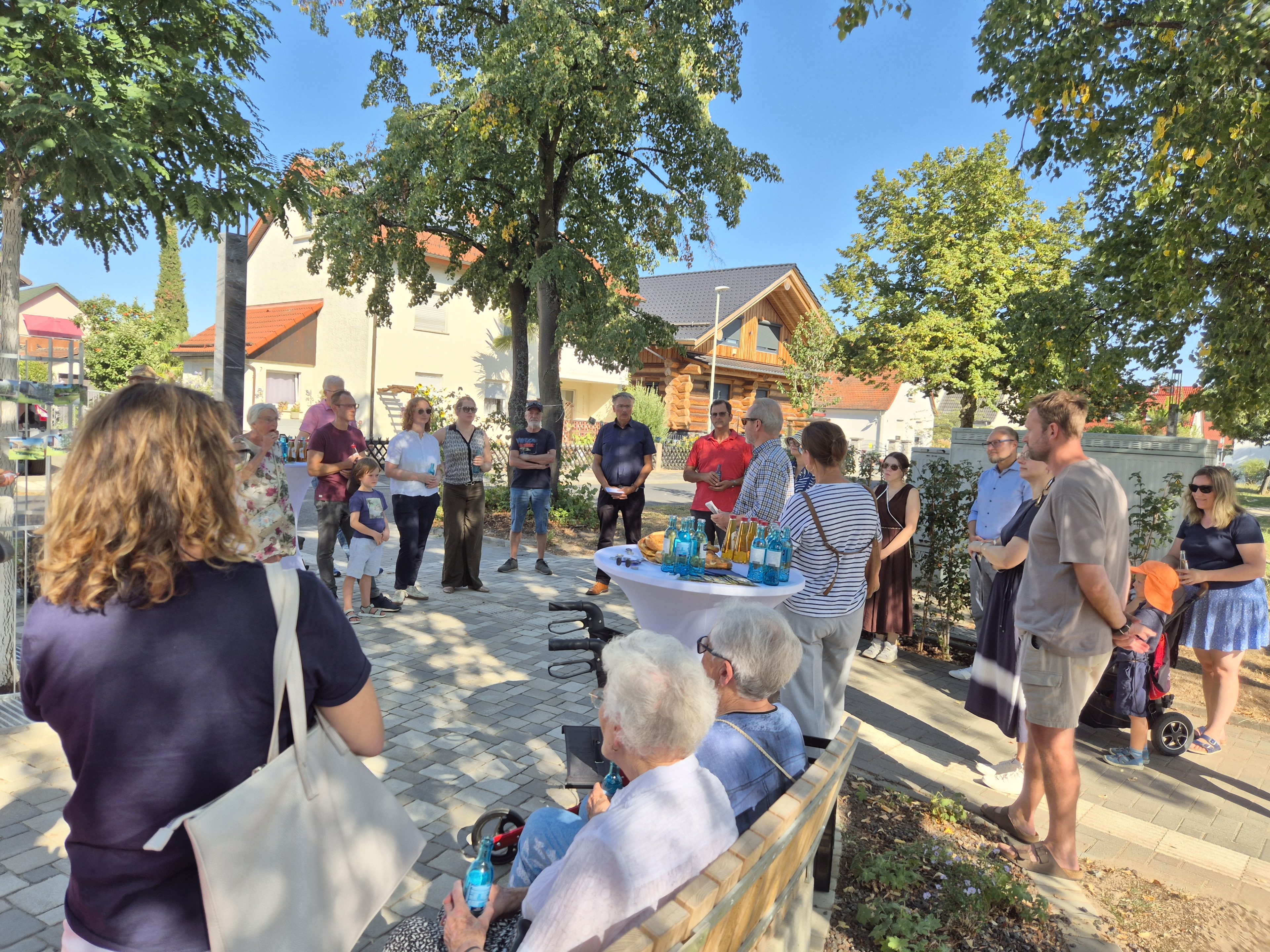 Feier mit rund 20 Menschen und einem neugestalteten Platz in Kelsterbach mit Bäumen, Bänken und Getränken